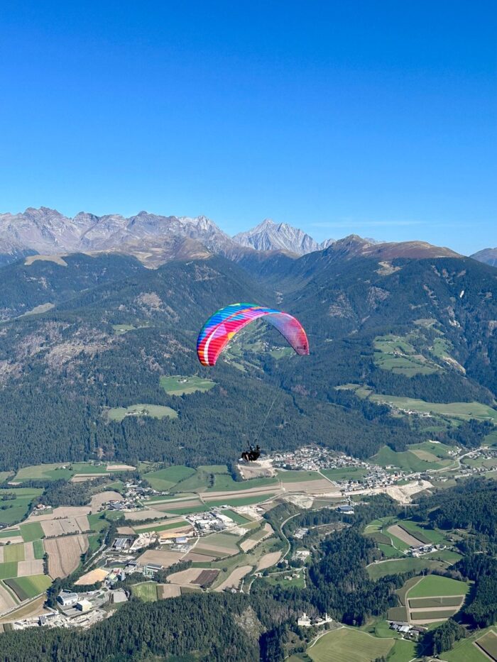 Tandemový paragliding nad Kronplatzem s výhledem na hory a údolí