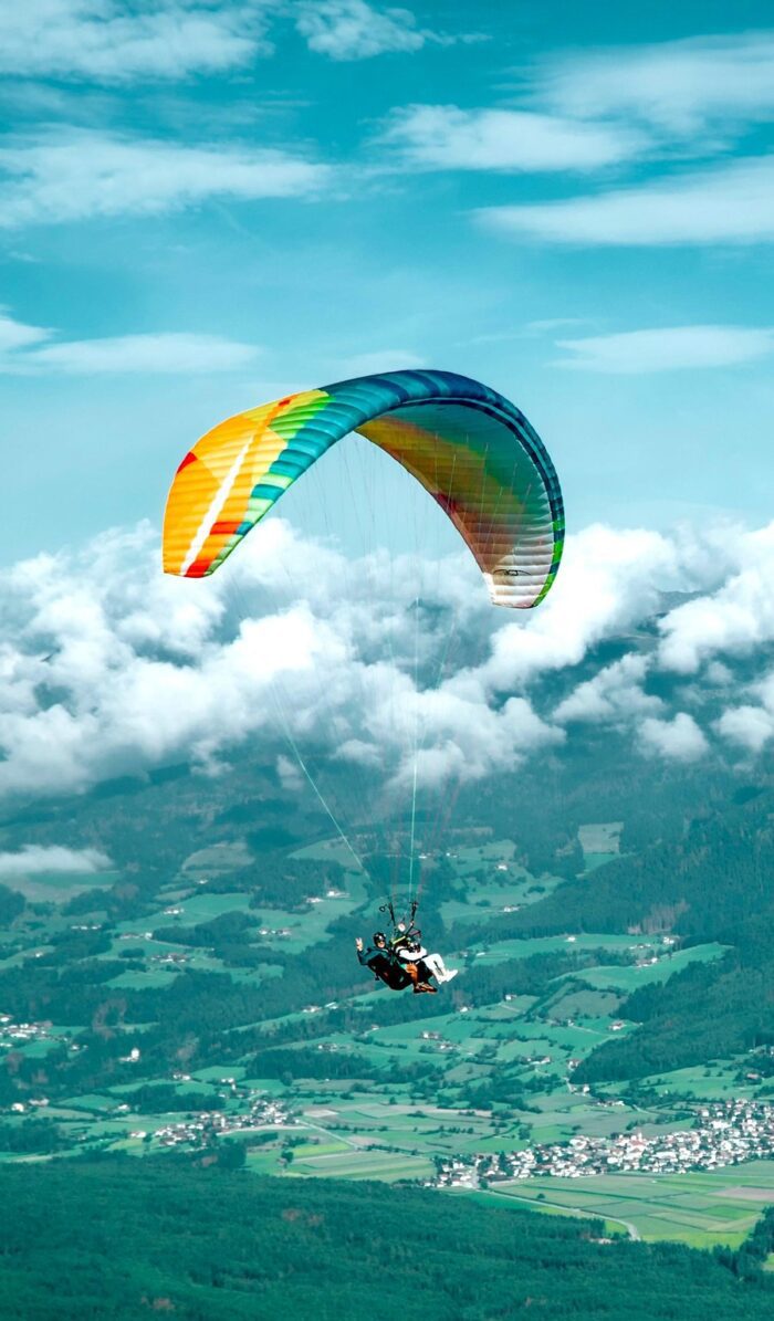 Tandemový paragliding nad Kronplatzem s výhledem na oblaka a údolí